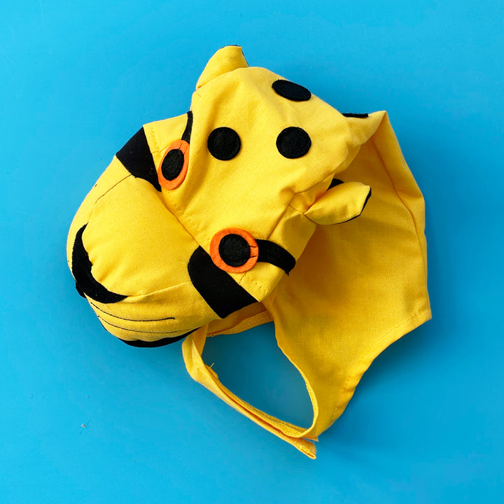Bright yellow cotton cheetah costume hat with a stuffed snout and felt eyes. Displayed on a bright blue background.