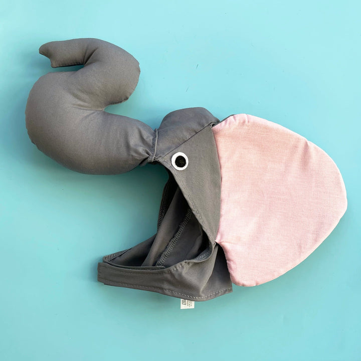 Grey cotton elephant costume hat with a stuffed, curved trunk, large pink ears and felt eyes. Displayed on a light blue background.