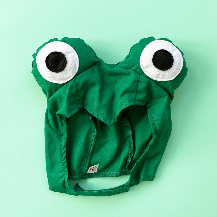 Bright green frog costume hat with large padded eyes. Displayed on a light green background.