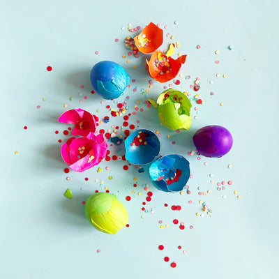 colorful eggs full of confetti broken on a blue background