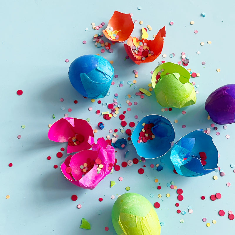 colorful eggs full of confetti broken on a blue background