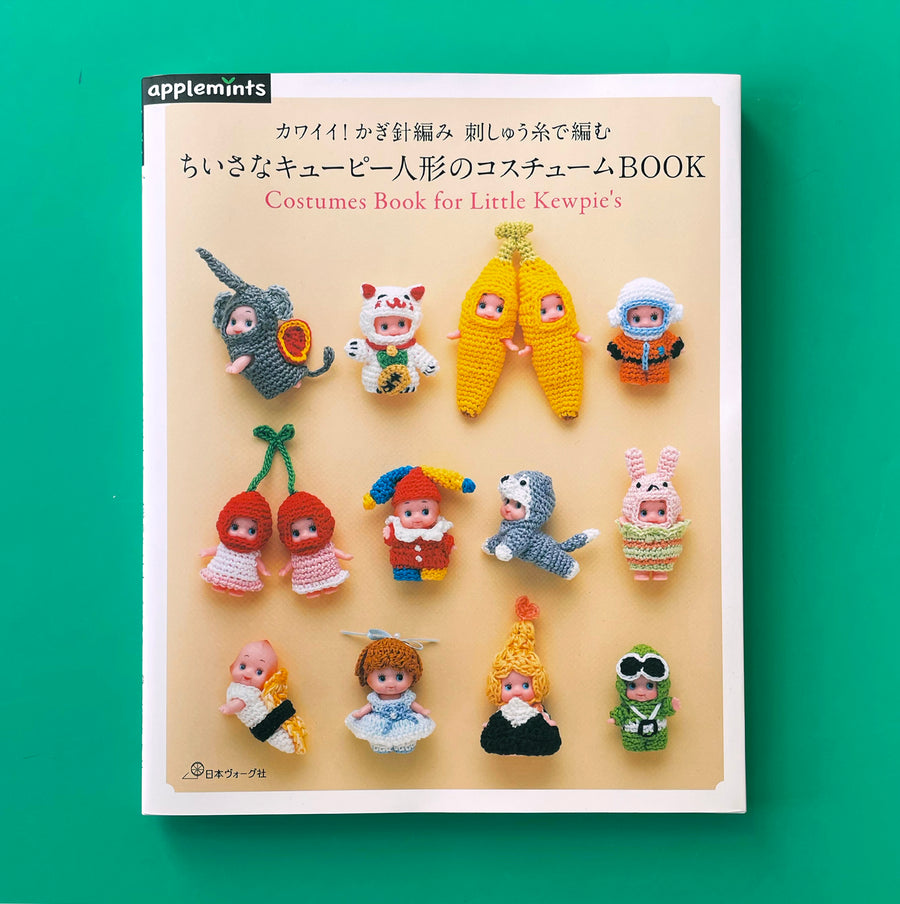 Costume Book for Little Kewpies on a green background. The book cover features 14 small Kewpie dolls in unique and absurd crocheted costumes, including an elephant, bananas and sushi.
