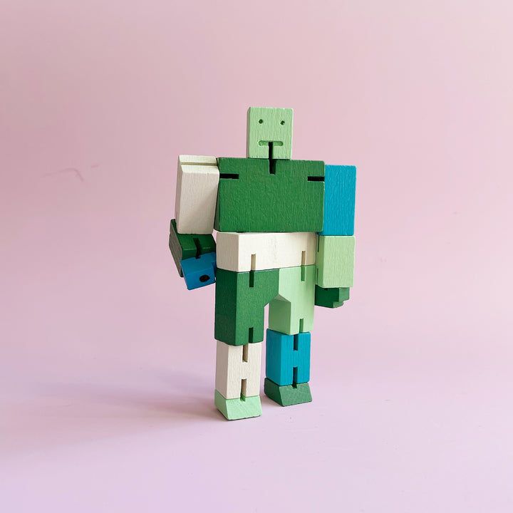 A small folding wooden robot toy in many shades of green standing up.