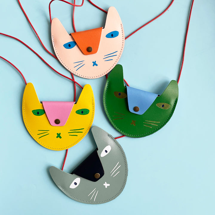 Several colorful cat-shaped purses on a light blue background.