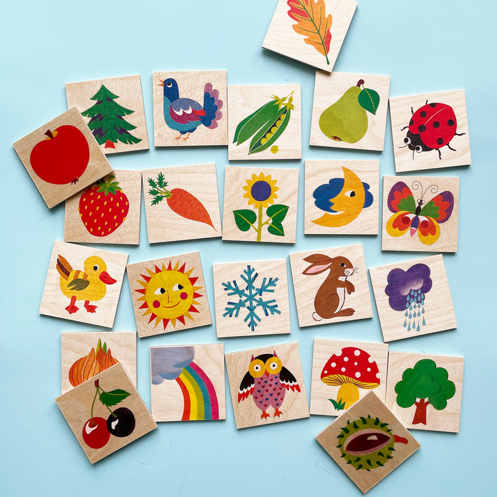 A loose grid  of  painted wooden memory game pieces on a light blue background
