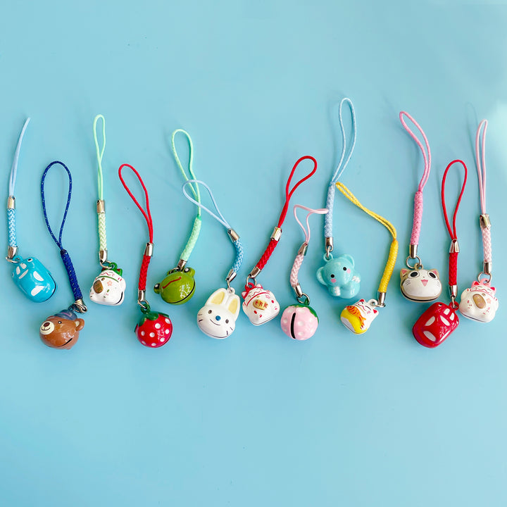 Several colorful and decorative bell charms laying in a line on a blue background