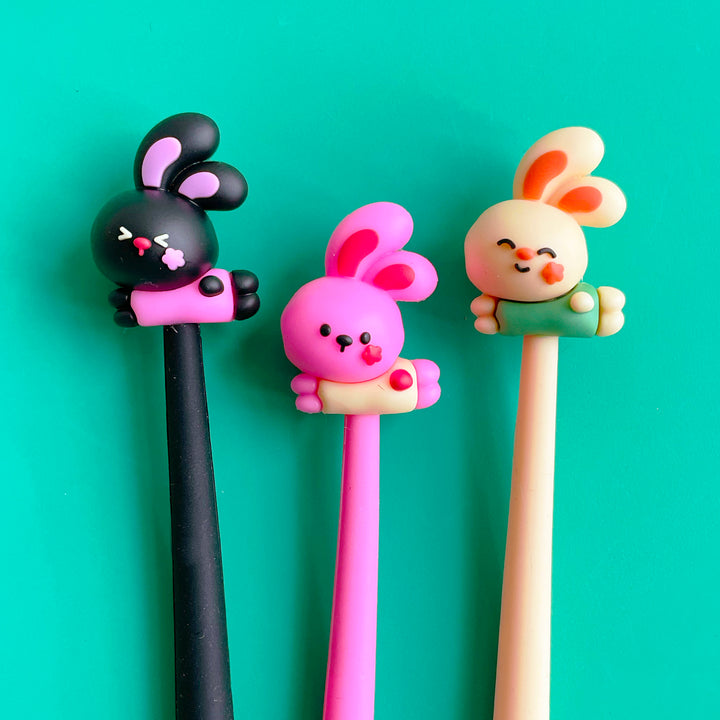 Three cartoonish rabbit pens in black, bright pink and peach.