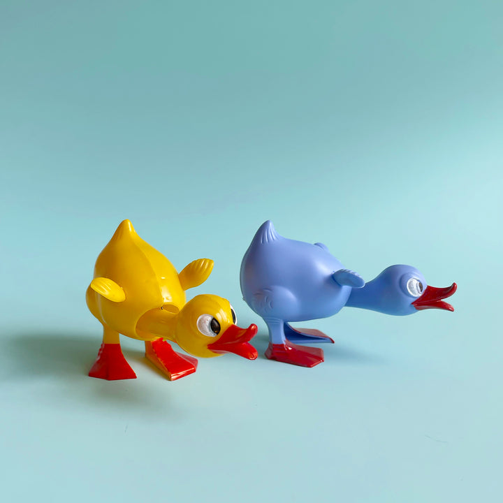 Two duck bobblehead figurines, one yellow, one light blue.