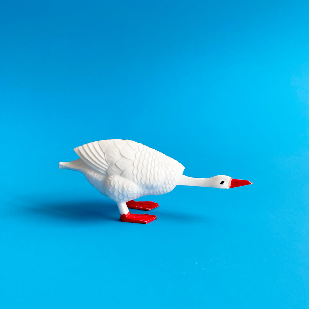 Small goose bobblehead in profile on a blue background