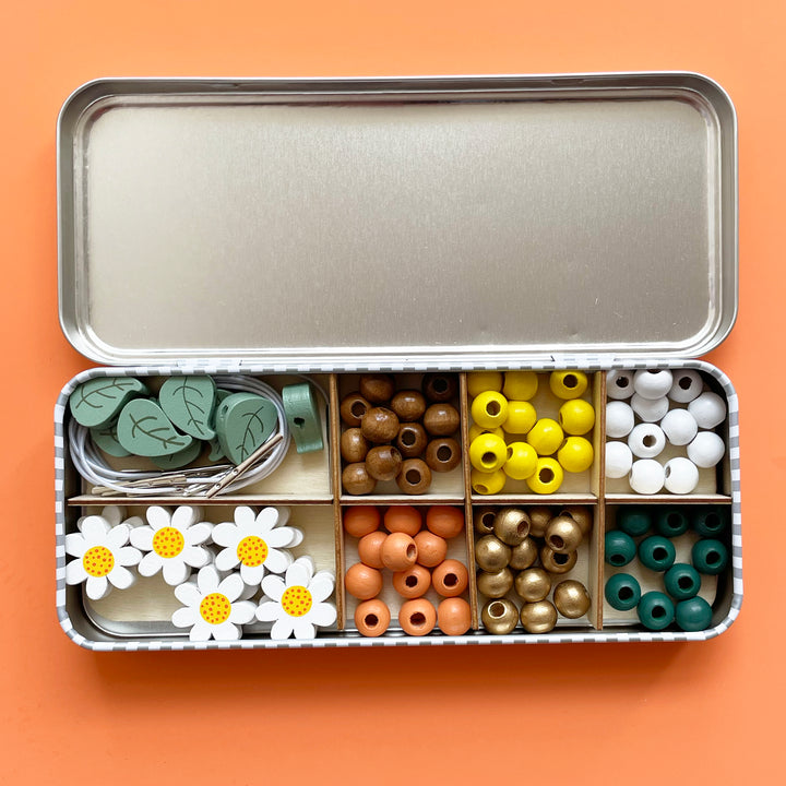 A colorful wooden beading kit in a tin with compartments