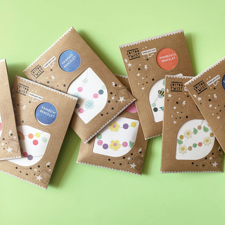 Several small bead kids in illustrated brown paper envelopes on a green envelope