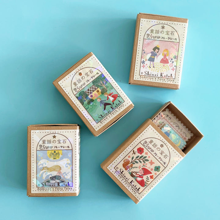 Four matchboxes illustrated with fairytale scenes. One box is open, showing some shimmery stickers inside.