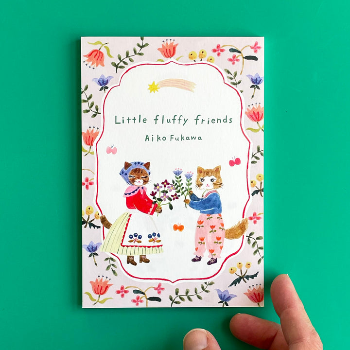A pack of "Little Fluffy Friends" postcards on a green background