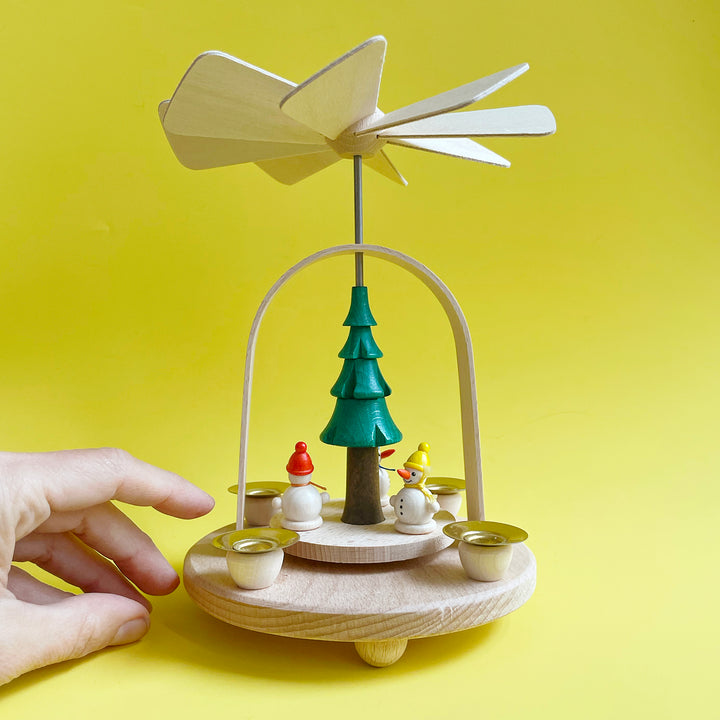 Small traditional wooden candle pyramid from Germany. Features a simple arch, stylized tree and three small snowmen with colored hats.