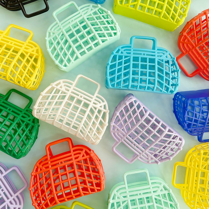 A group of colorful, small, vintage-style jelly baskets artfully scattered on a light blue background.