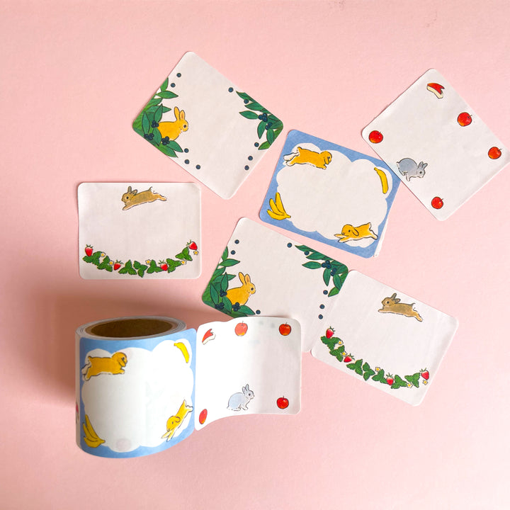 Several rabbit illustrated labels and a roll of labels on a pink background.