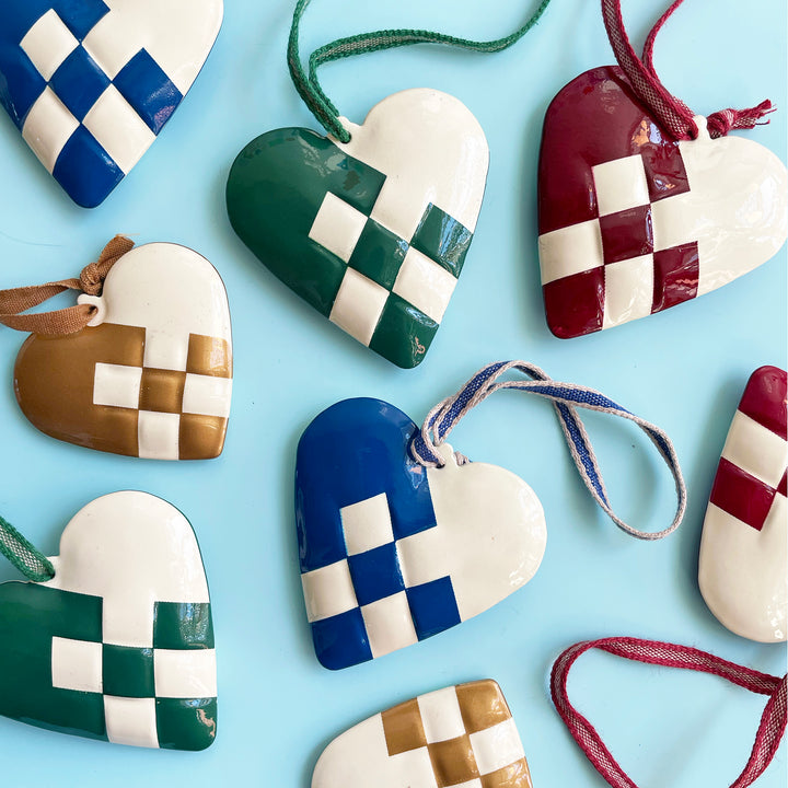 Colorful metal hearts designed to look like traditional Danish paper hearts, artfully scattered on a light blue background.
