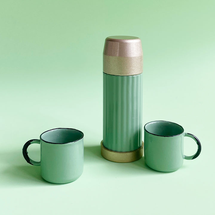Miniature thermos and mug set in mint-colored metal displayed on a light green background.