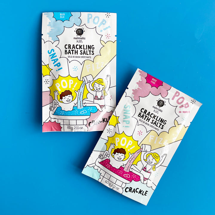 Two packages of Nailmatic crackling bath salts on a blue background. Packaging features a cartoon drawing of kids playing in a bath filled with colorful water.