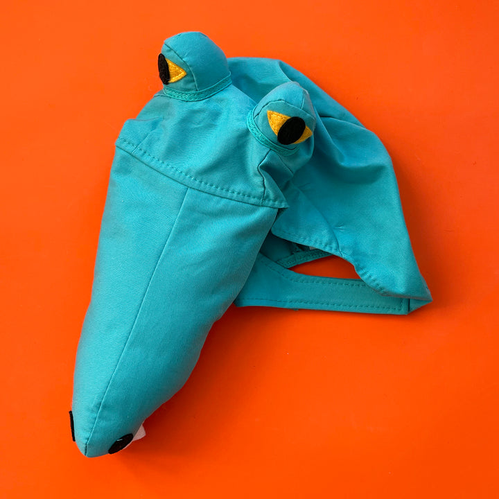 Green cotton crocodile costume hat with large stuffed snout and raised felt eyes. Displayed on a bright orange background.