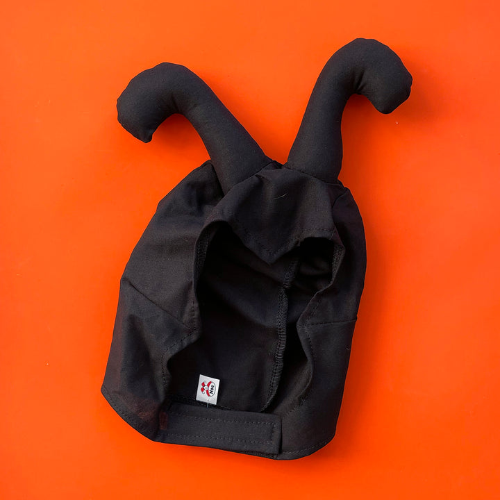 Black cotton insect costume hat with padded antennae. Displayed on a bright orange background.
