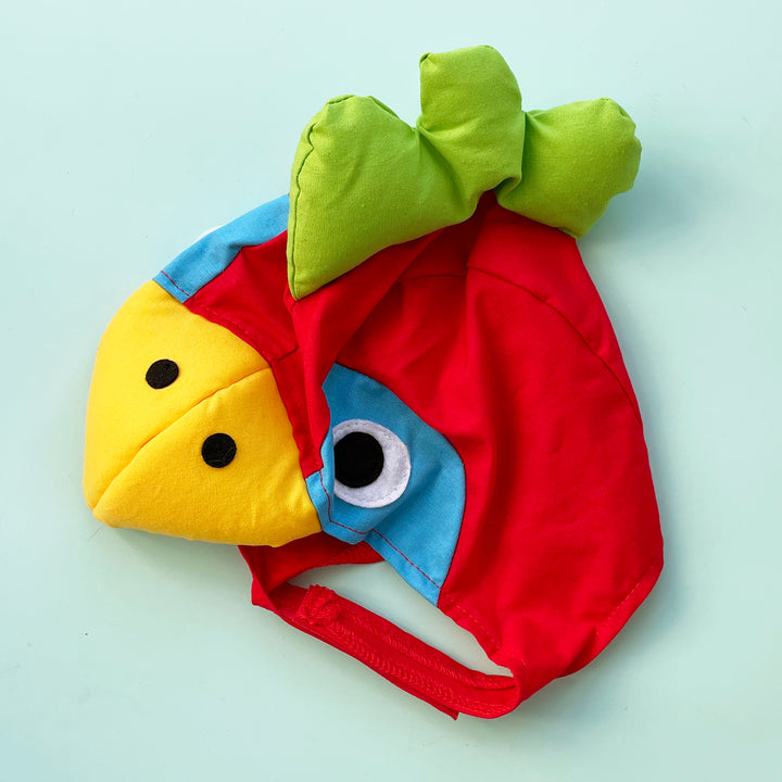 Red cotton parrot costume hat with colorful accents, yellow padded beak and green padded crest. Displayed on a light blue background.