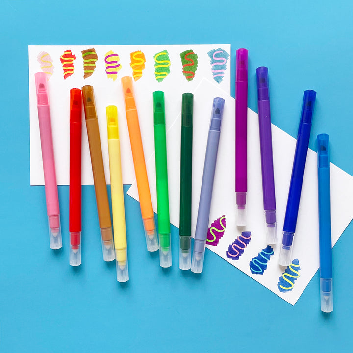 Twelve Switcheroo Color Changing Markers from Ooly displayed on white paper with sample color swatches for each marker.