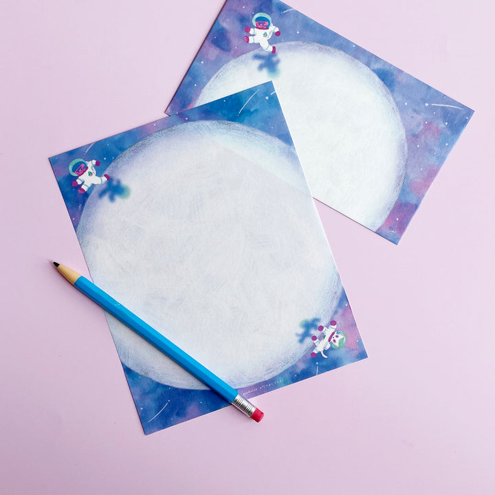 A space themed letter set and blue mechanical pencil on a pink background.