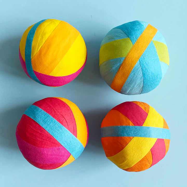 Four colorful surprise balls arranged in a grid on a light blue background.