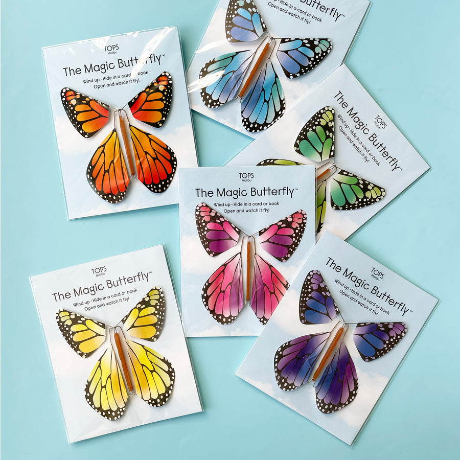 Six packaged Magic Butterflies in a variety of colors fanned out on a light blue background.