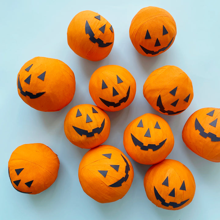 A group of orange jack-o-lantern inspired surpise balls displayed on a light blue background.