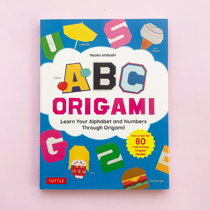 ABC Origami book displayed on a pink background. Book cover features origami projects including the letters U, S, and G, the number 2, a hamburger, an ice crem and a little girl.