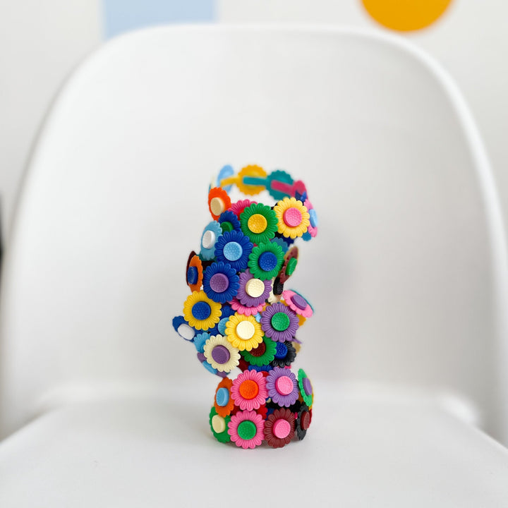 Several plastic flower bracelets staked on top of one another on a white background.