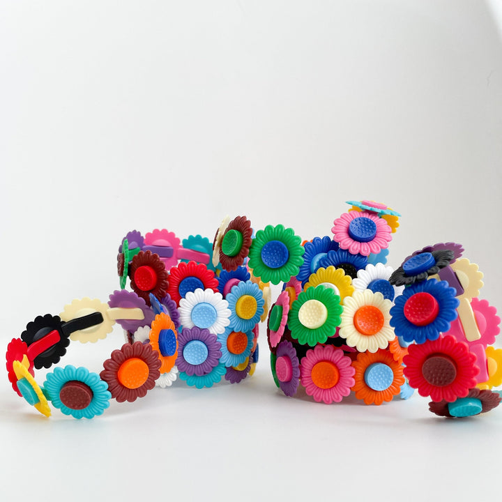 Several plastic floral bracelets piled on one another on a white background.