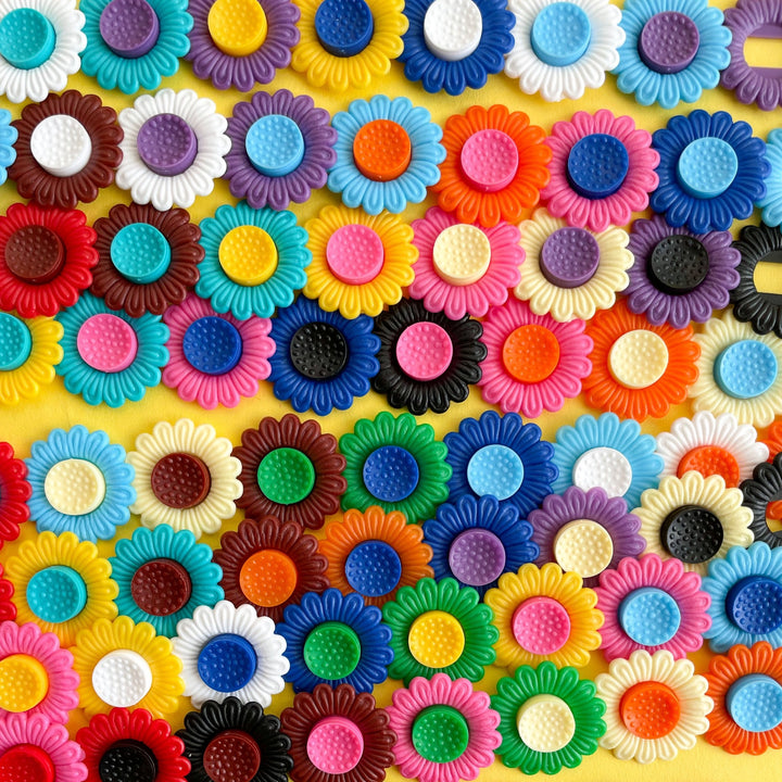 Several rows of multi colored plastic flower clips on a yellow background.