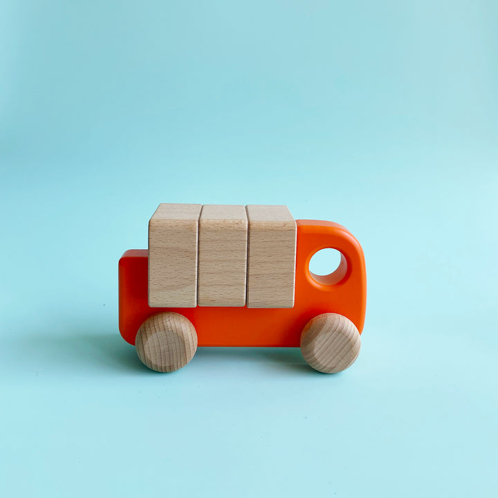 Orange wooden truck toy with three wooden blocks on it's back