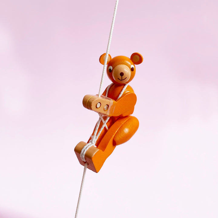 Bear shaped wooden figurine on a light pink background.
