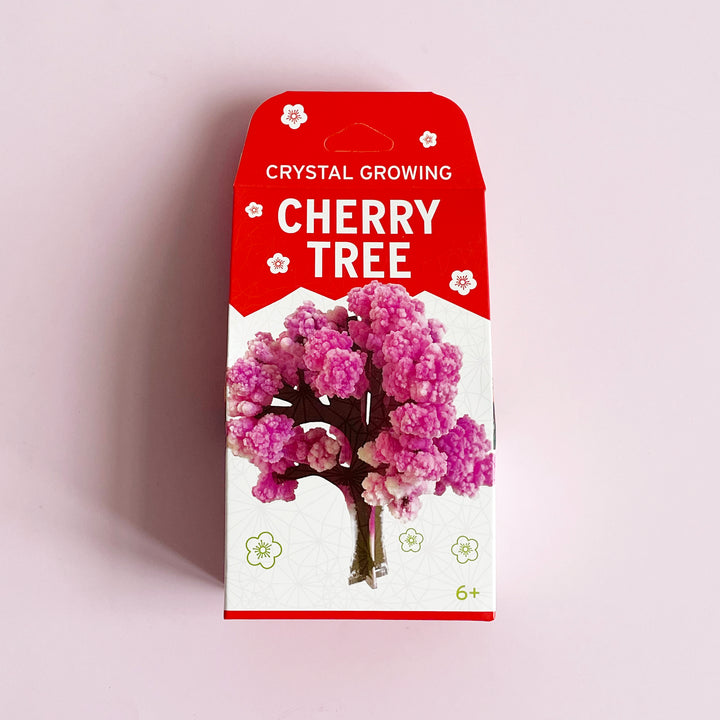 A boxed Crystal Growing Cherry tree kit on a pink background.