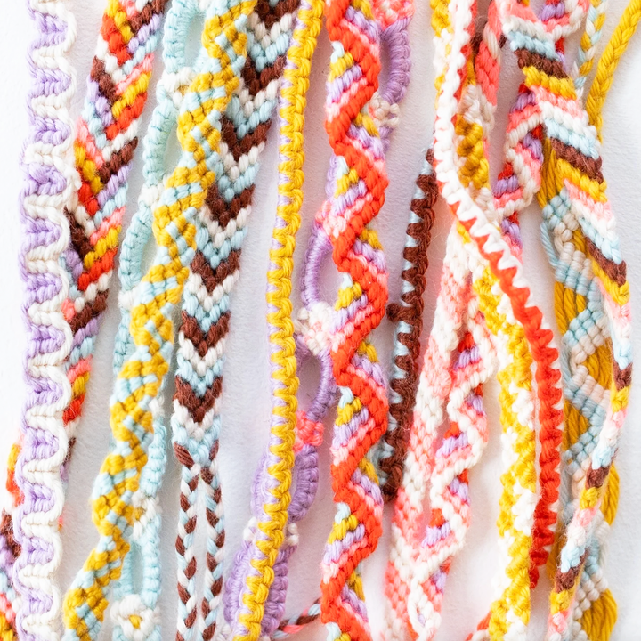 A bundle of colorful friendship bracelets in a variety of colors and patterns.