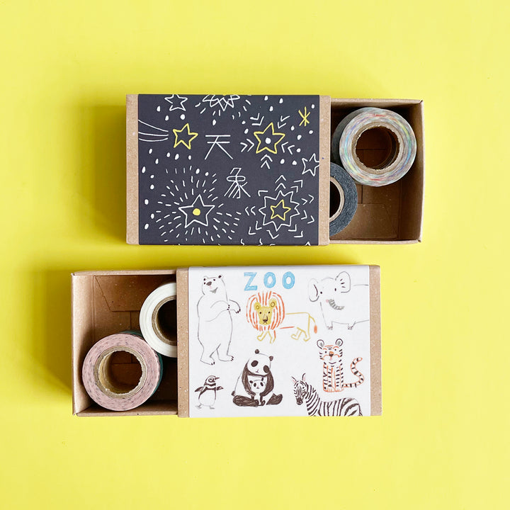 two matchboxes pused partially open to reveal tiny rolls of washi tape inside.