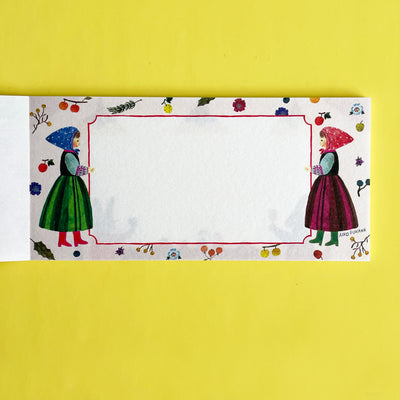 This page of the memo pad has two illustrated people in dresses on either side of the white writing area, on a fruit and floral patterned background.
