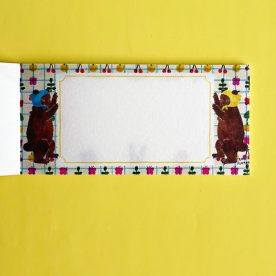 This page of the memo pad has two illustrated brown bears in bonnets holding either side of the white writing area, on a patterned background.