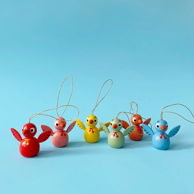 Several colorful wooden bird ornaments on a blue background. 