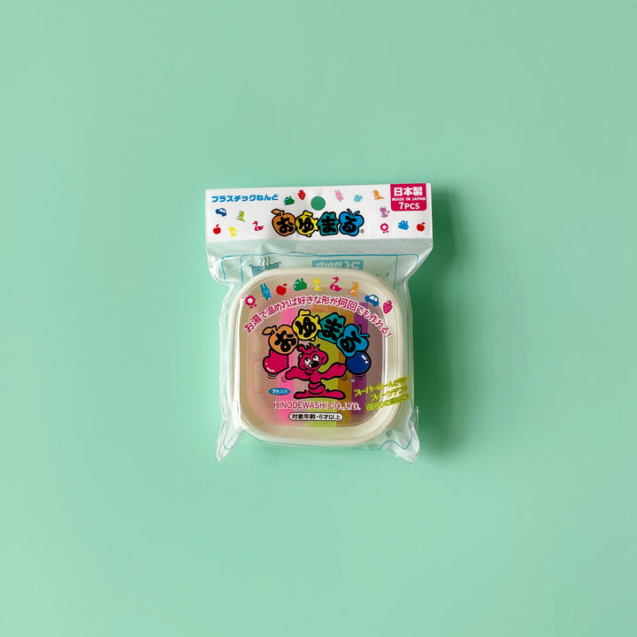 A package of seven pieces of colorful hot water clay displayed on a light green background. The packaging uses bright eon colors and a playful cartoon design. All text is in Japanese.