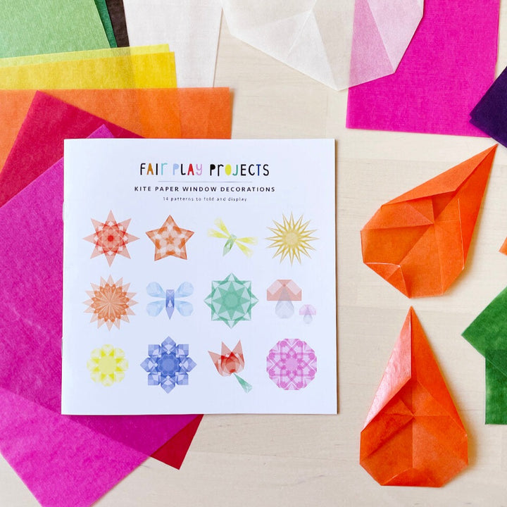 Kite paper and a kite paper instruction booklet laying on a wooden background
