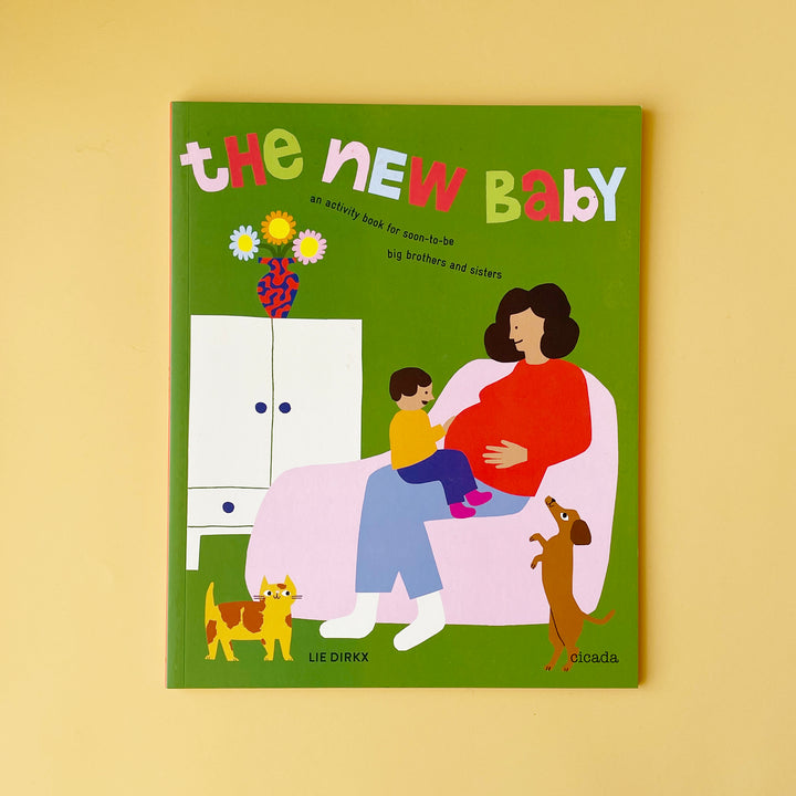 A copy of the book "The New Baby". The cover features a colorful illustration of a pregnant mom and a child sitting on her lap.