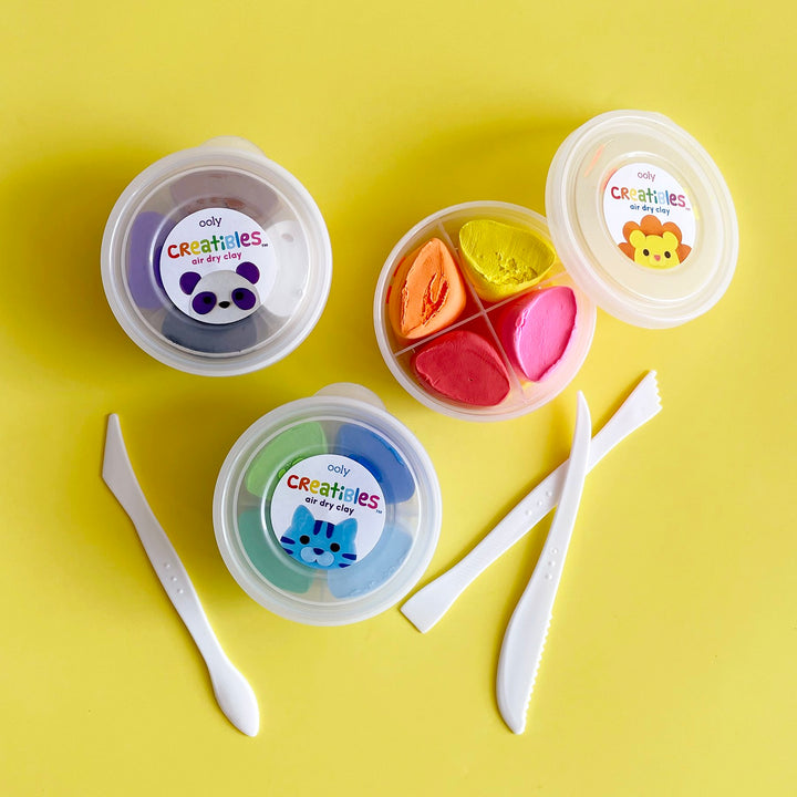 Three containers of multi colored clay on a yellow background.