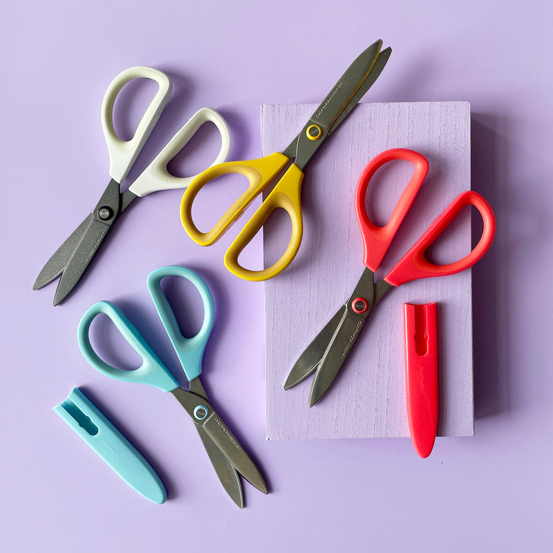 Four colorful scissors arranged on a purple background