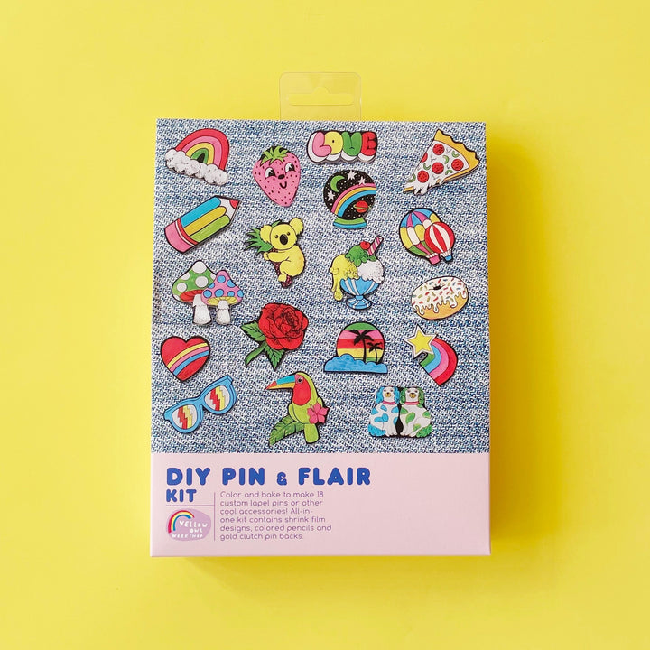 Package of DIY Pin & Flair Kit by Yellow Owl Workshop displayed on a bright yellow background. The box features a variety of handmade shrink plastic pins including a rose, sunglasses, a koala and an ice cream sundae.