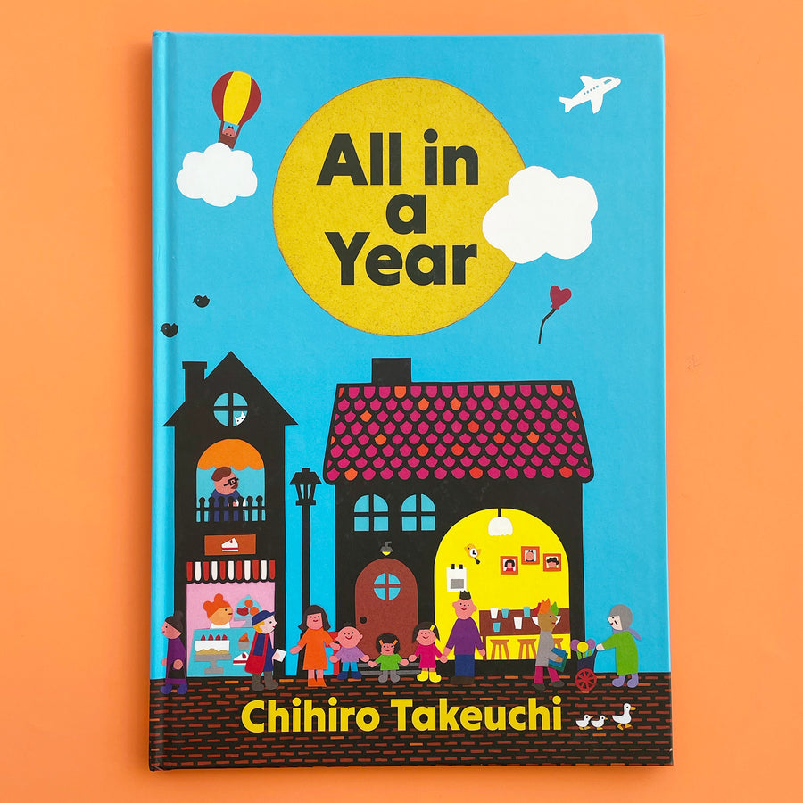 All In A Year book on an orange background, Book cover features a stylized, bold illstration on a nighborhood street bustling with people. The title of the book fits in a big, round yellow sun in the sky. 